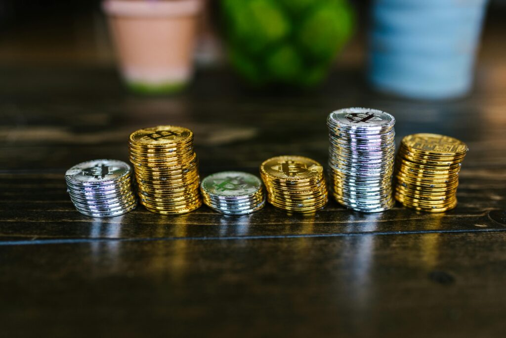 Pile of shiny gold and silver cryptocurrency coins on a wooden table.